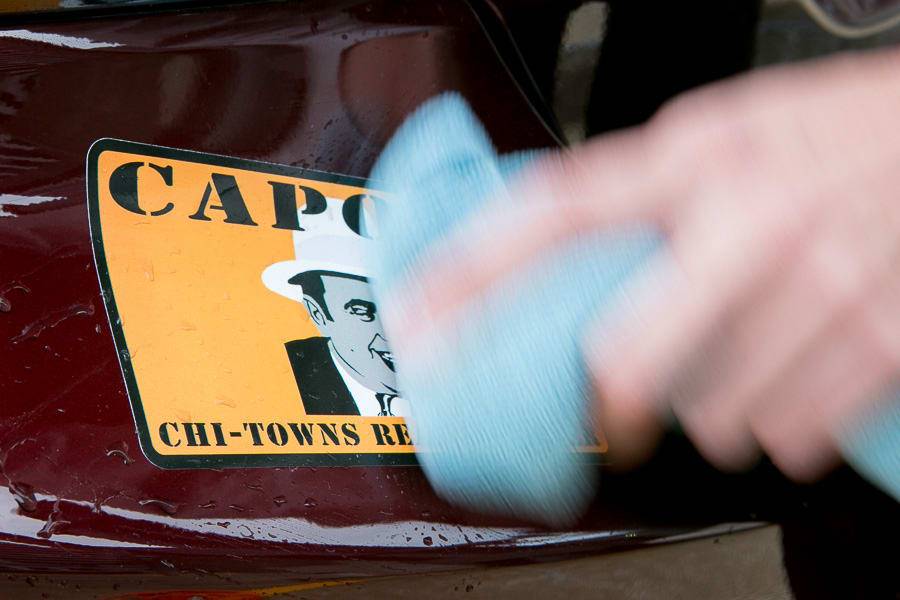 Wiping away dirt around the sticker on a car