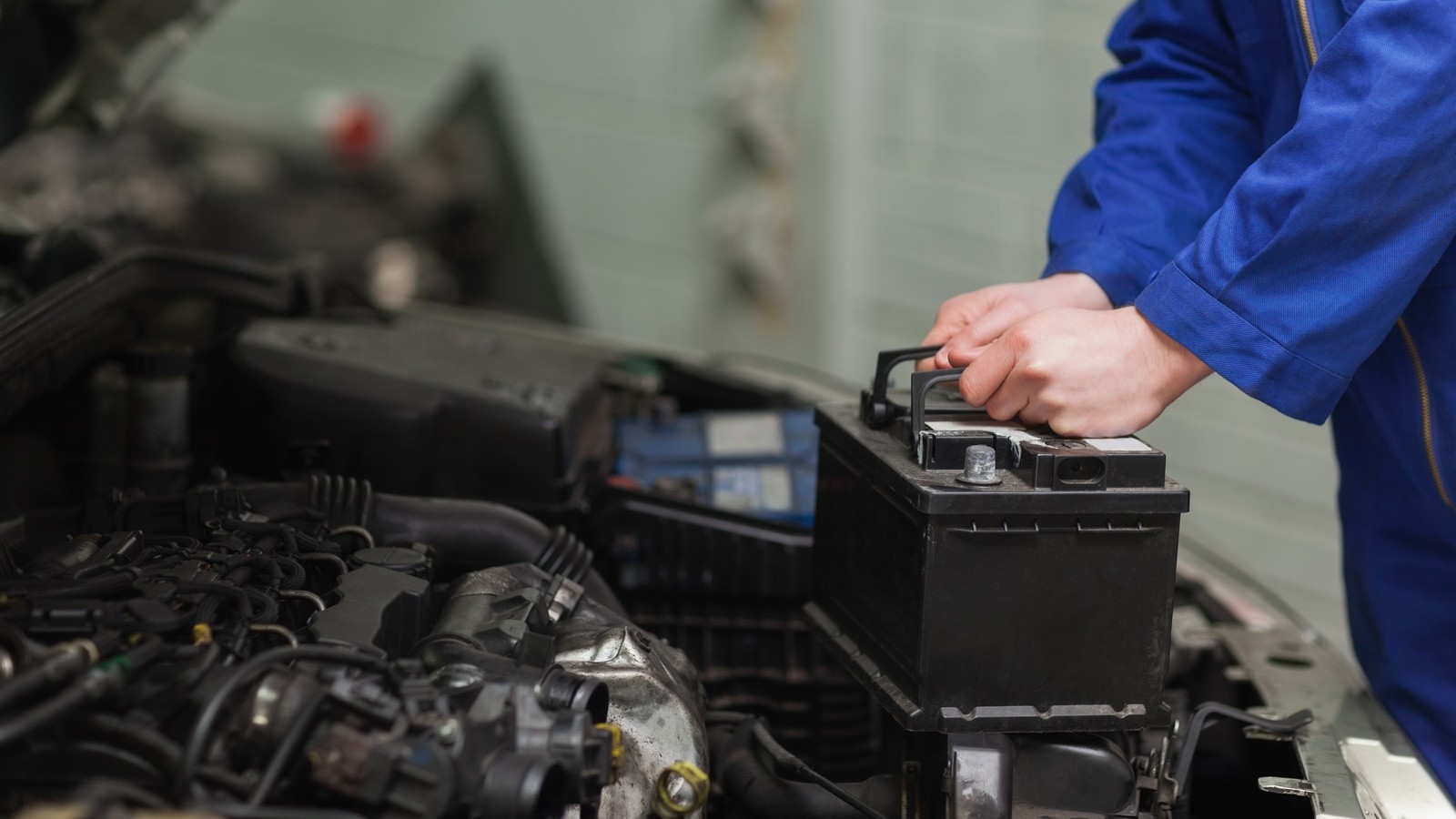 Male mechanic changing car battery